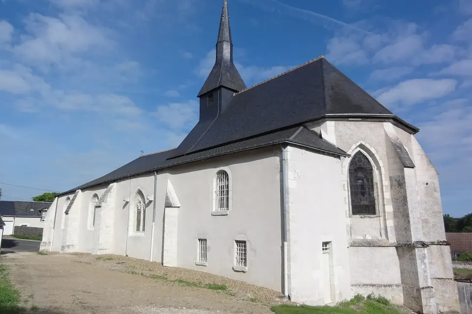 Église rurale blanche aux contreforts de pierre, toit d'ardoise et fine flèche, sous un ciel bleu