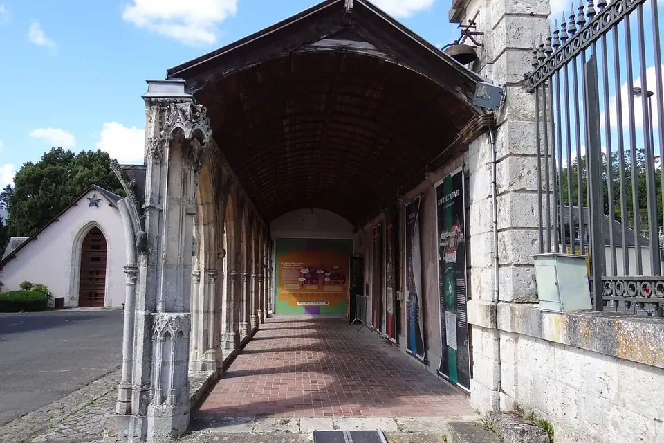 Galerie de cloître gothique couverte d'une charpente, le long d'un bâtiment de pierre