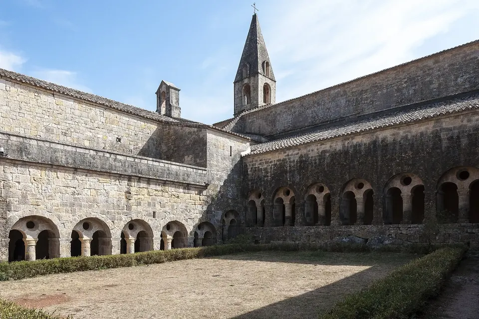 Galeries de cloître romanes en pierre et clocher carré d'une abbaye